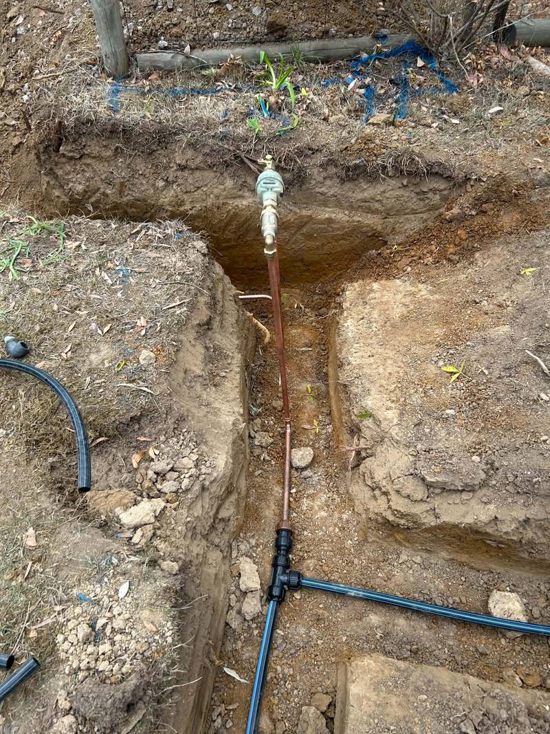 New water service in an open trench: meter at the surface, copper riser and blue-line poly water main running off